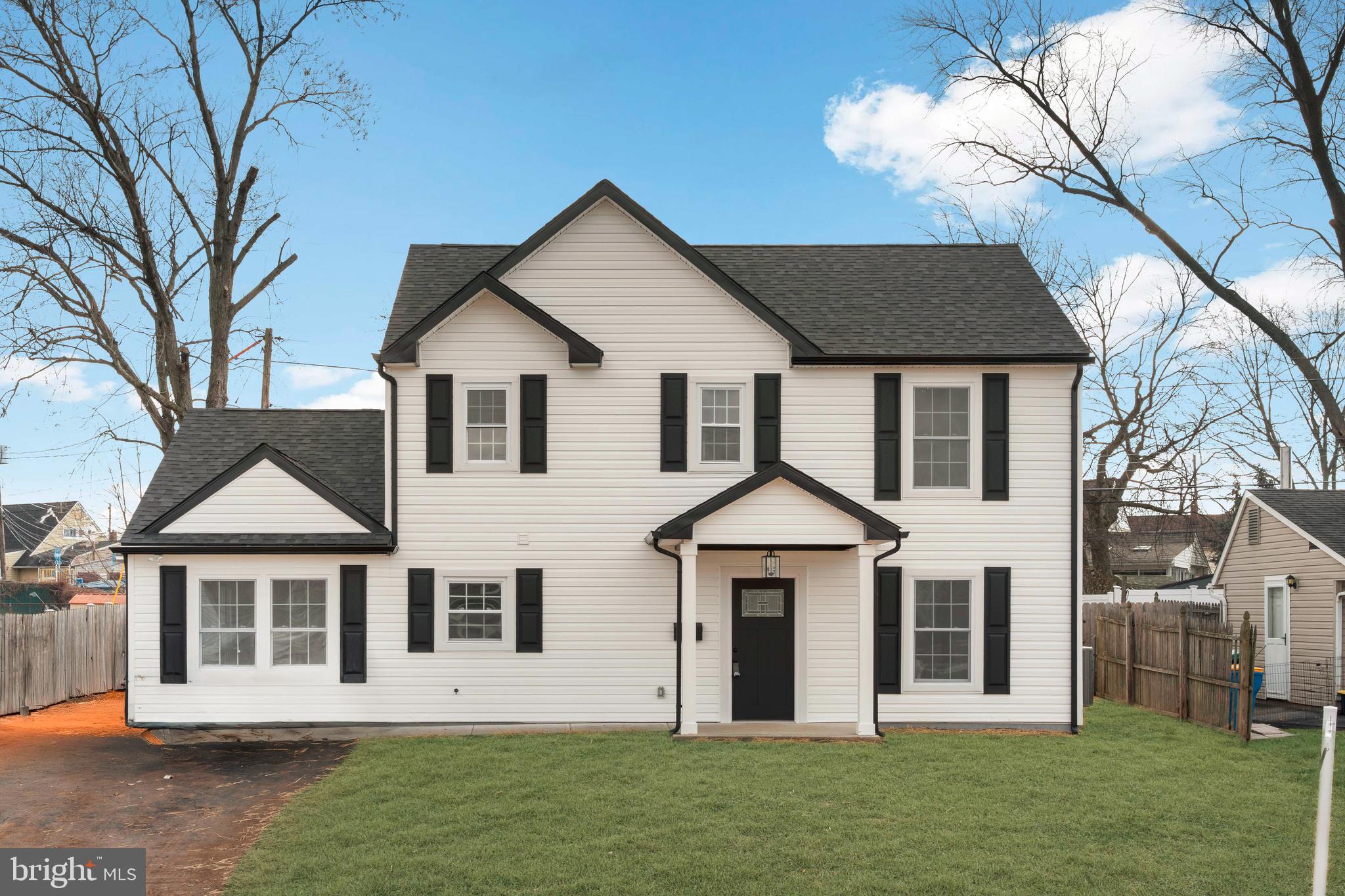 a view of a white house with a big yard and large trees