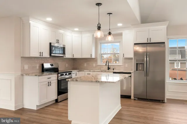 a kitchen with stainless steel appliances granite countertop a refrigerator a stove a sink and a microwave