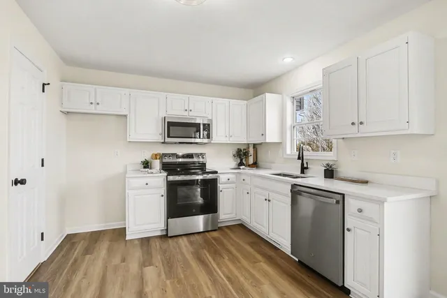 a kitchen with granite countertop white cabinets stainless steel appliances and sink