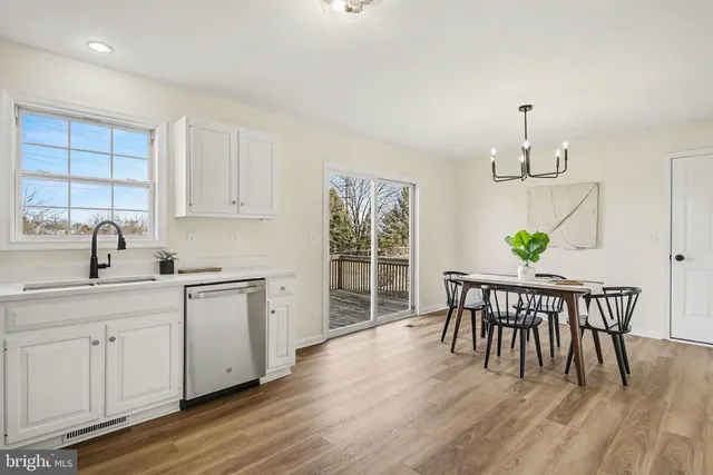 a dining room with wooden floor a chandelier a wooden table and chairs