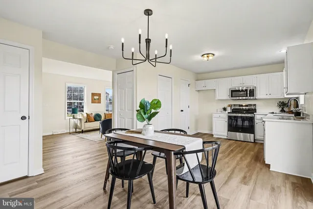 a view of a dining room and livingroom with furniture wooden floor a chandelier