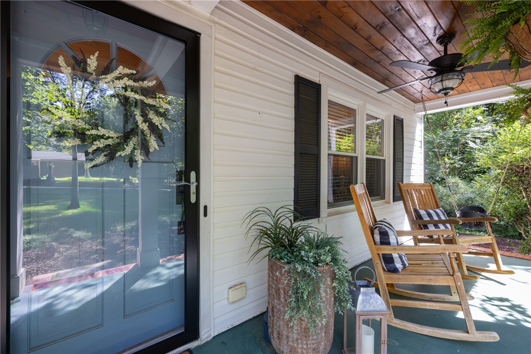 203 Augusta Road Clemson, SC 29631 - Photo 4 of 31 A welcoming front porch features comfortable wooden rocking chairs and a wood-paneled ceiling.