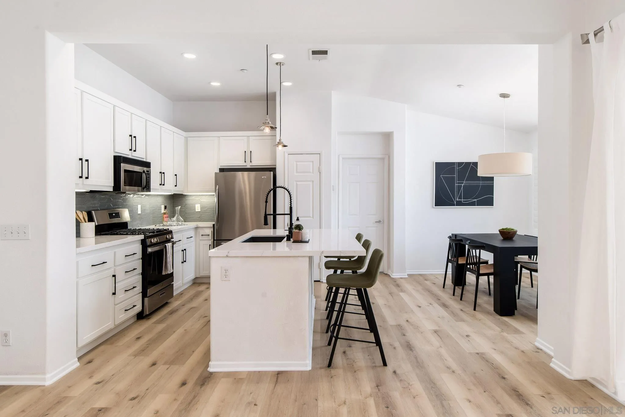 1694 Avery Road San Marcos, CA 92078 - Photo 6 of 22 a kitchen with stainless steel appliances a stove top oven a refrigerator a dining table and chairs with wooden floor