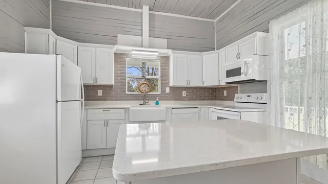 a kitchen with stainless steel appliances granite countertop a refrigerator a sink and white cabinets
