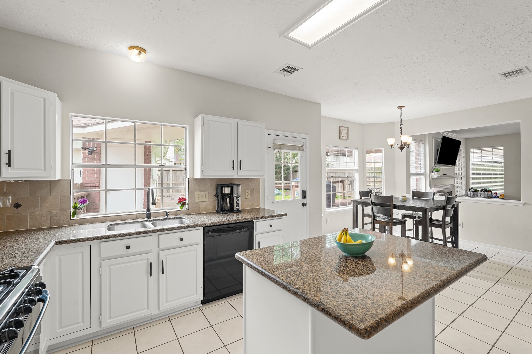 16114 Kintyre Point Road Houston, TX 77095 - Photo 23 of 44 This bright kitchen features white cabinetry, granite countertops, and modern appliances. It opens to a cozy dining area with large windows, offering plenty of natural light. Perfect for cooking and entertaining.