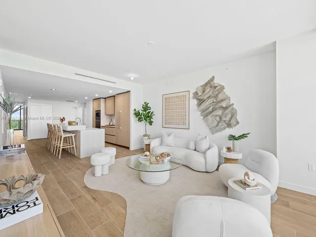 a living room with kitchen island a wooden floor and a chandelier
