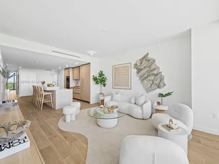 a living room with kitchen island a wooden floor and a chandelier