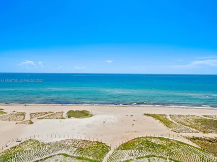 a kitchen with stainless steel appliances kitchen island granite countertop a refrigerator a stove a sink and white cabinets with wooden floor