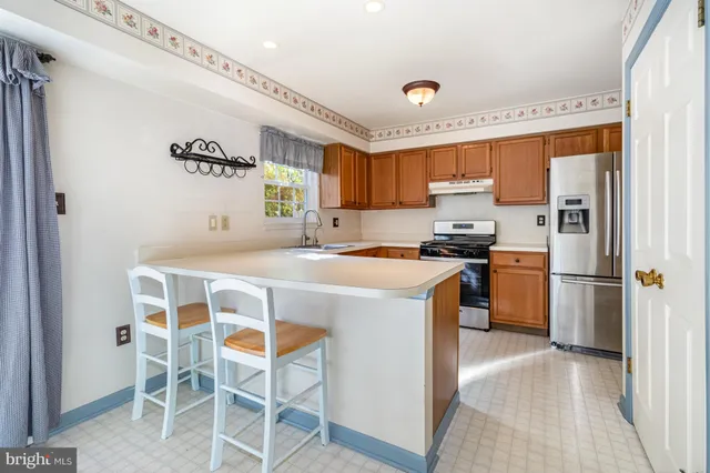 a kitchen with a refrigerator a stove and white cabinets with wooden floor