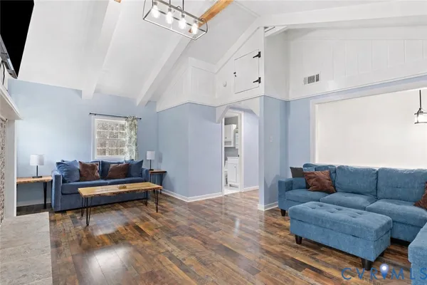 a living room with furniture a flat screen tv and a chandelier