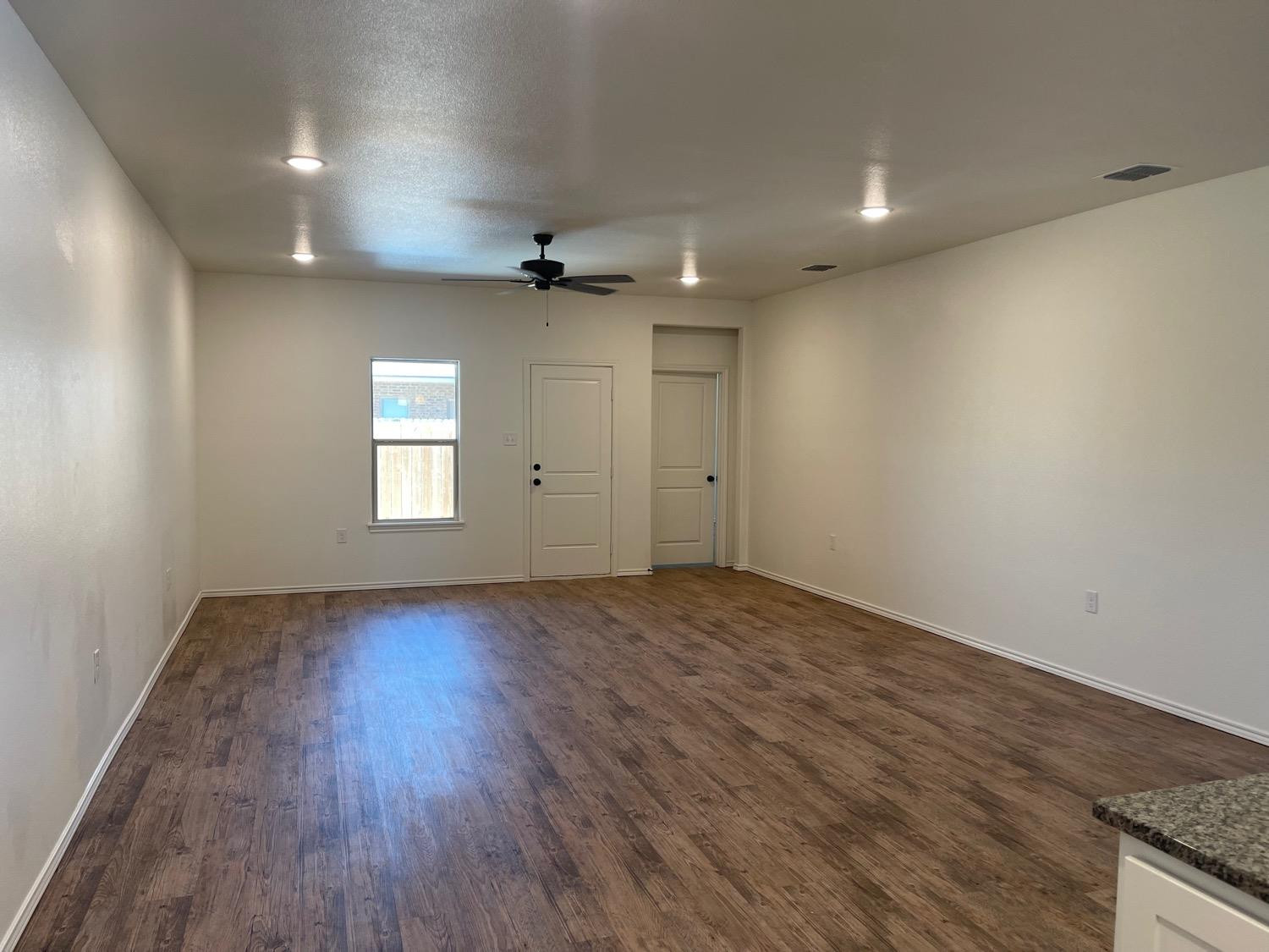 5536 Kemper Street Lubbock, TX 79416 - Photo 4 of 13 an empty room with wooden floor and windows