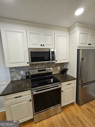 a kitchen with cabinets stainless steel appliances and wooden floor