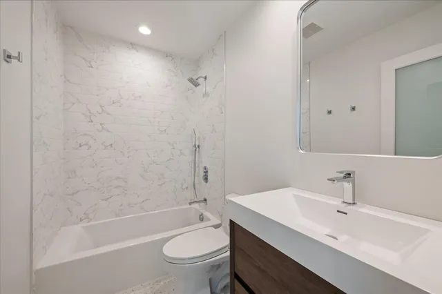a bathroom with a bathtub shower sink mirror vanity and a toilet