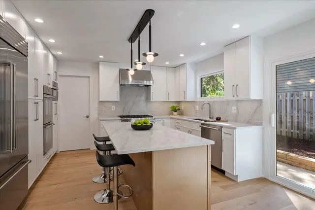 a kitchen with kitchen island a stove a table and chairs in it