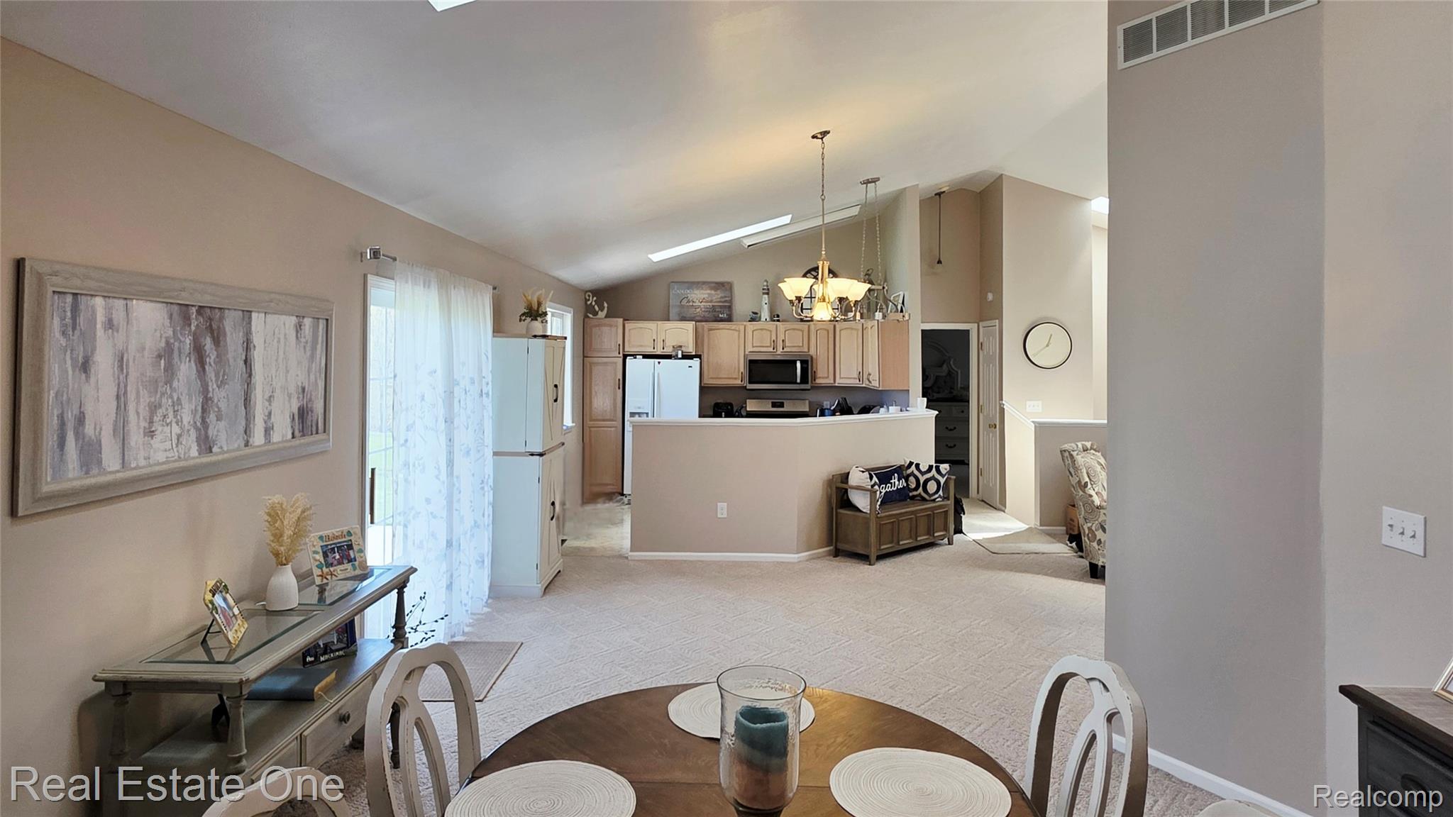 8751 Highland Road Watervliet, MI 49098 - Photo 9 of 16 Dining room with suspended lighting, light colored carpet, lofted ceiling, and a skylight