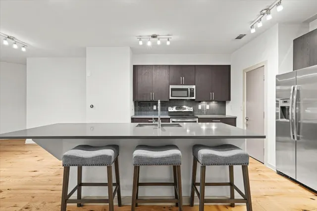 a kitchen with stainless steel appliances granite countertop a refrigerator a stove a sink a dining table and chairs