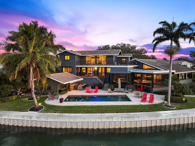 a dining hall with stainless steel appliances kitchen island granite countertop a dining table chairs and a refrigerator