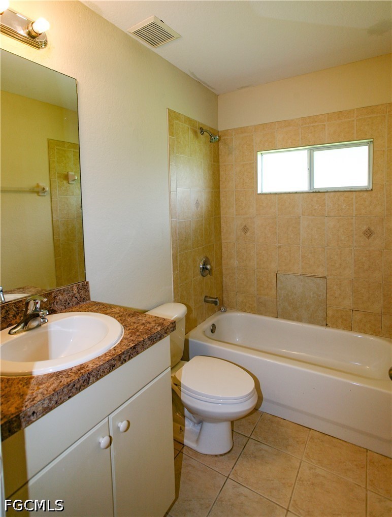 4614 25th Street Southwest Lehigh Acres, FL 33973 - Photo 14 of 15 a bathroom with a granite countertop sink a toilet a mirror and bathtub