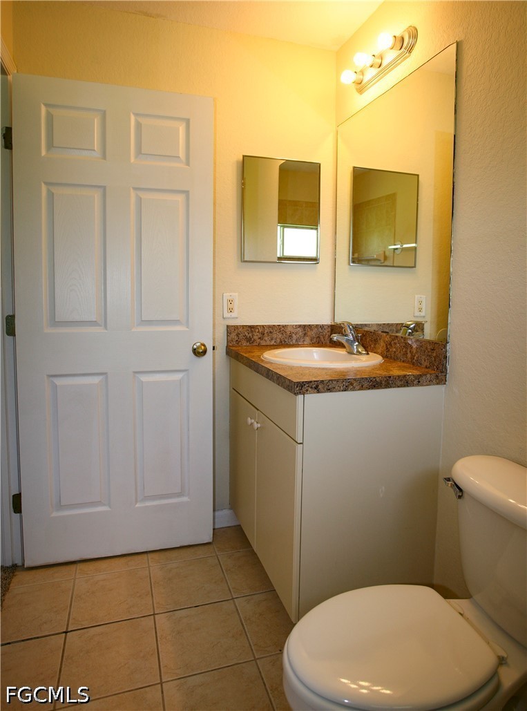 4614 25th Street Southwest Lehigh Acres, FL 33973 - Photo 9 of 15 a bathroom with a granite countertop sink a mirror and a toilet