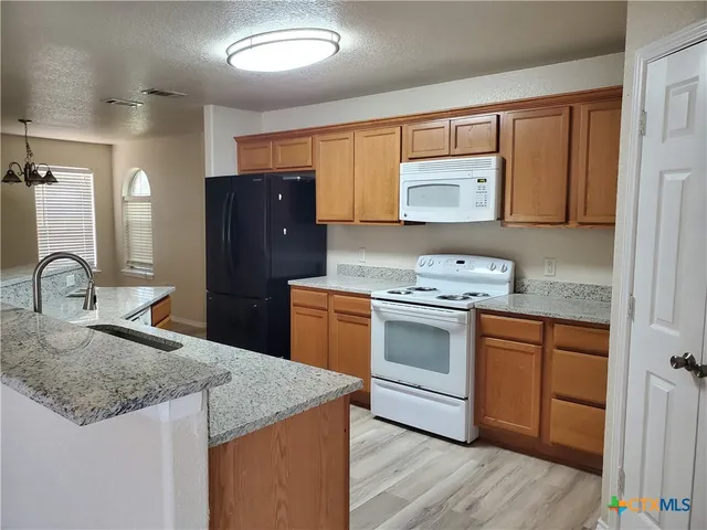 a kitchen with granite countertop a sink stove and refrigerator