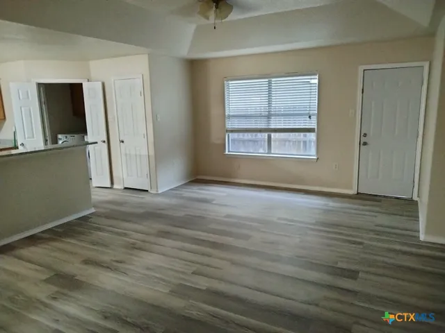 an empty room with wooden floor and windows