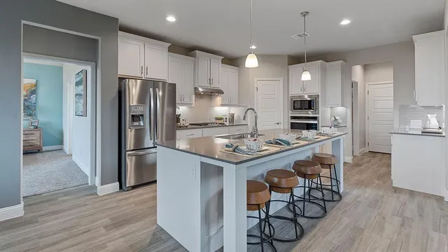 a kitchen with kitchen island granite countertop a sink cabinets and wooden floor