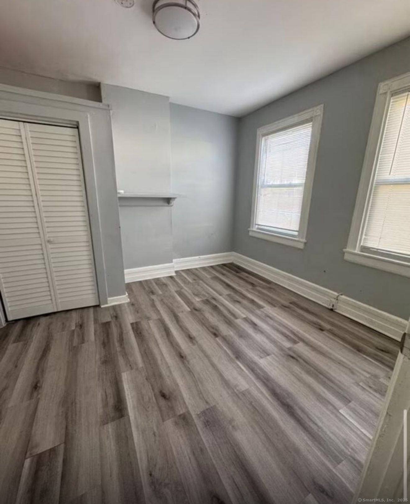 301 Dover Street, Unit 1 Bridgeport, CT 06610 - Photo 2 of 4 an empty room with wooden floor and windows
