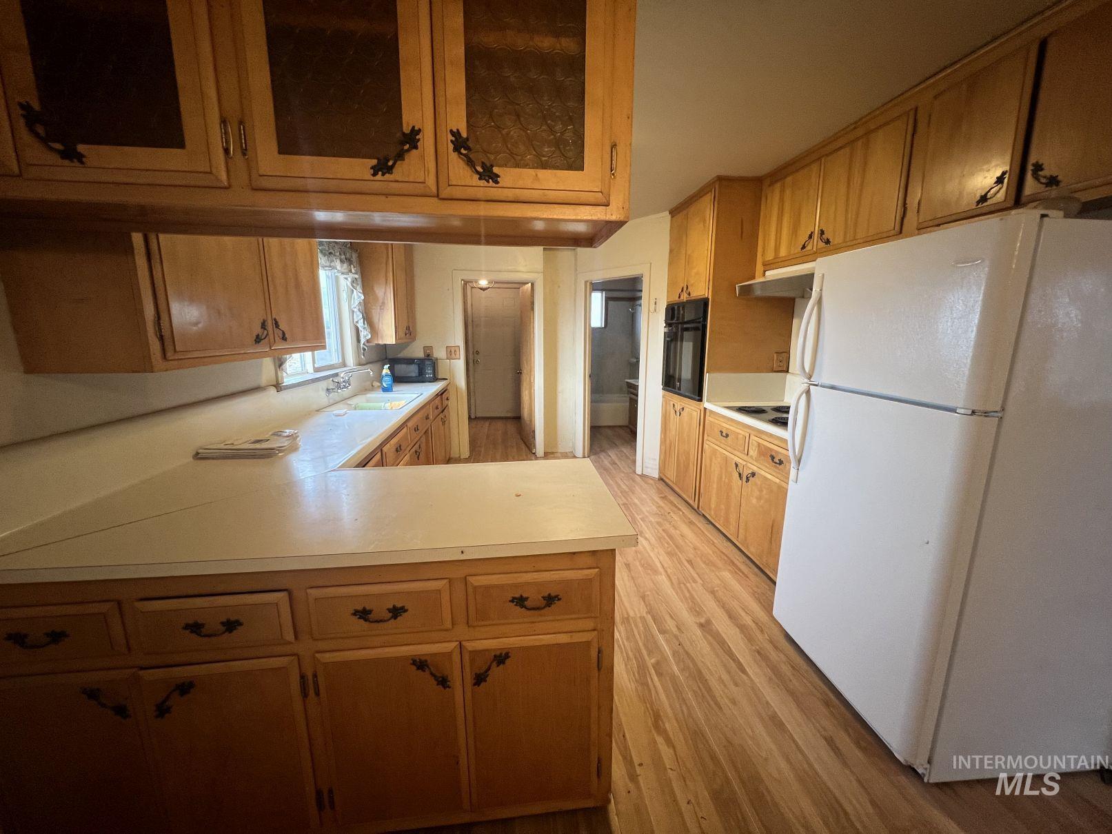 156 West 100 North Jerome, ID 83338 - Photo 3 of 15 Kitchen featuring freestanding refrigerator, glass insert cabinets, light countertops, and light wood-type flooring