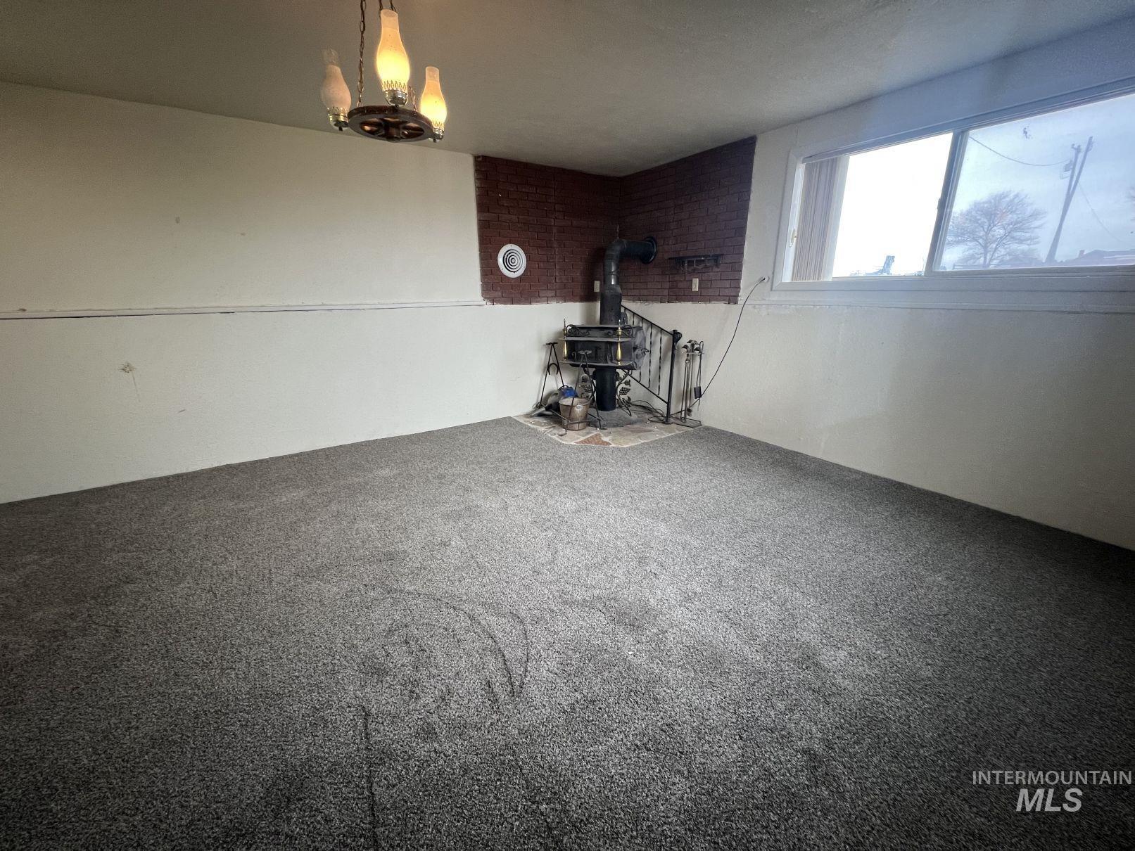 156 West 100 North Jerome, ID 83338 - Photo 9 of 15 Unfurnished living room featuring a wood stove, carpet, and a chandelier