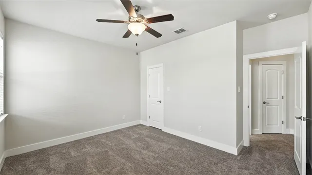 an empty room with a window and a fan