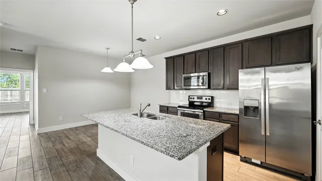 a kitchen with granite countertop a stove and a wooden floor