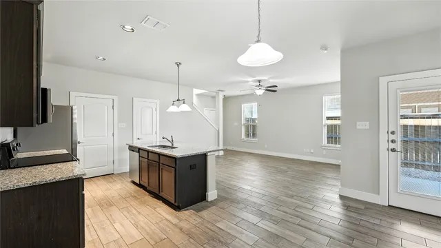 a kitchen with kitchen island granite countertop a stove a sink and a wooden floors