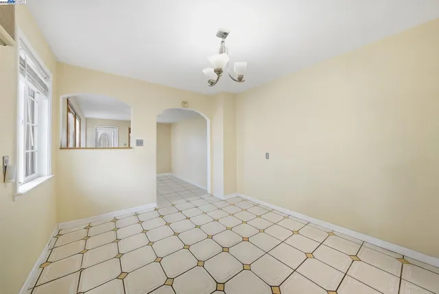 a view of an empty room and chandelier fan