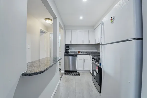 a kitchen with a refrigerator and white cabinets