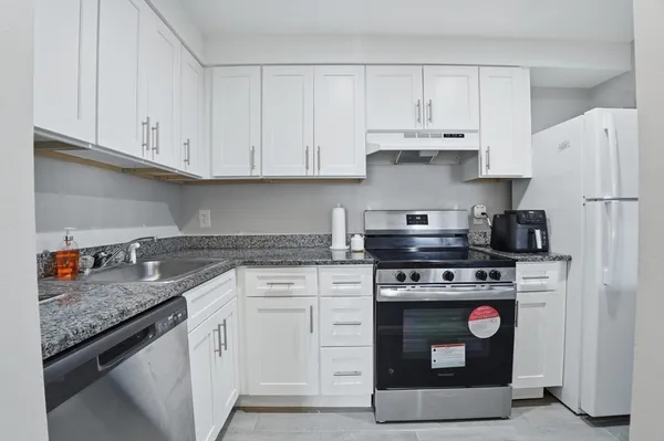 a kitchen with stainless steel appliances granite countertop a stove and white cabinets