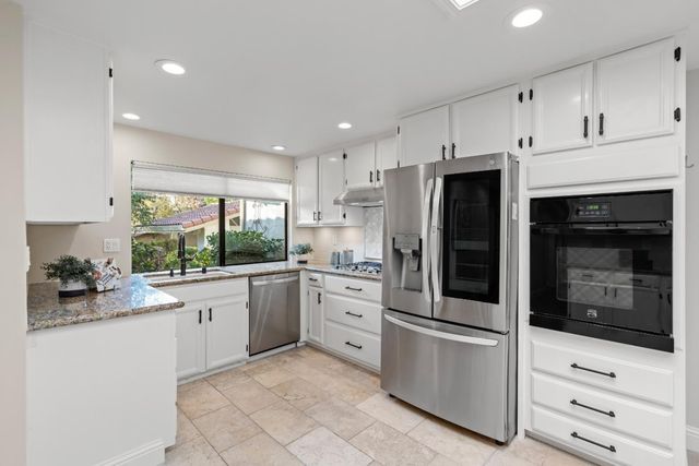 a kitchen with granite countertop white cabinets and stainless steel appliances