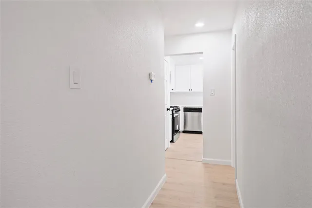 a hallway with wooden floor and a bathroom