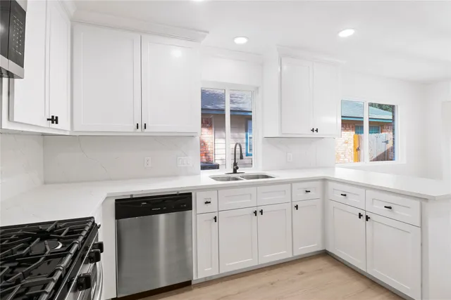 a kitchen with white cabinets and sink