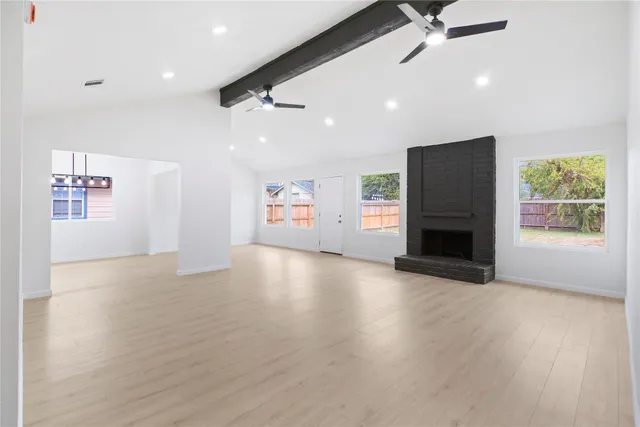 an empty room with windows fireplace and wooden floor