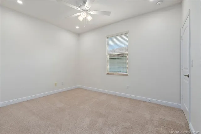 a view of an empty room with window and ceiling fan