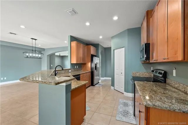 a large kitchen with granite countertop a sink and dishwasher a stove top oven with wooden floor