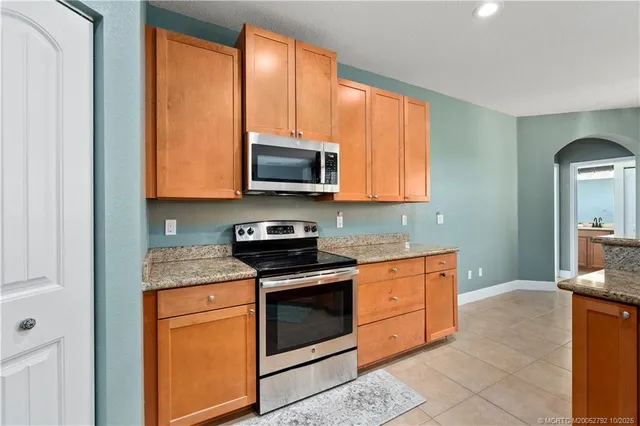 a kitchen with stainless steel appliances granite countertop a sink a stove and refrigerator