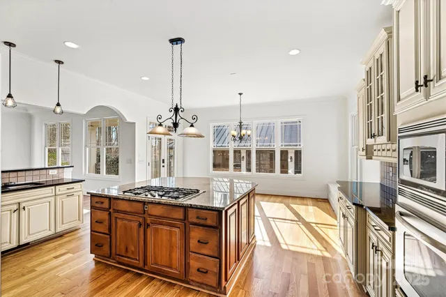 a kitchen with stainless steel appliances granite countertop a stove a sink and a wooden floors
