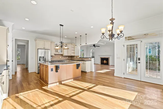 a large kitchen with granite countertop a stove a sink dishwasher a refrigerator and a fireplace with wooden floor