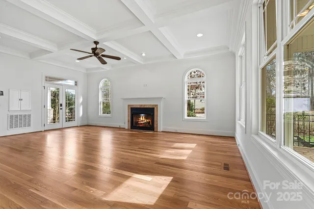 a view of an empty room with window and wooden floor