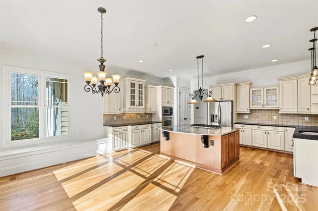 a large kitchen with stainless steel appliances kitchen island granite countertop a stove and white cabinets