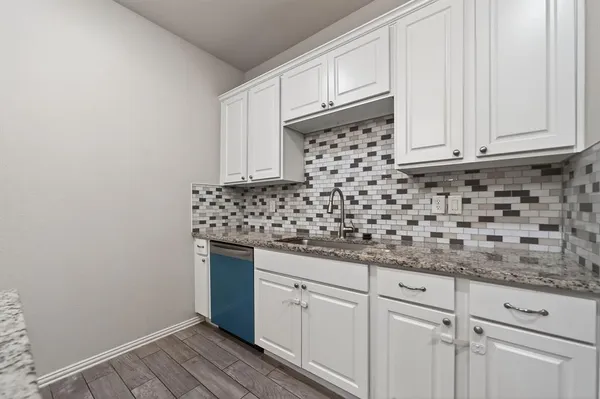 a kitchen with granite countertop white cabinets and sink