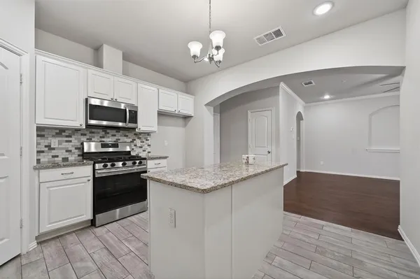 a kitchen with stainless steel appliances granite countertop a stove cabinets and microwave