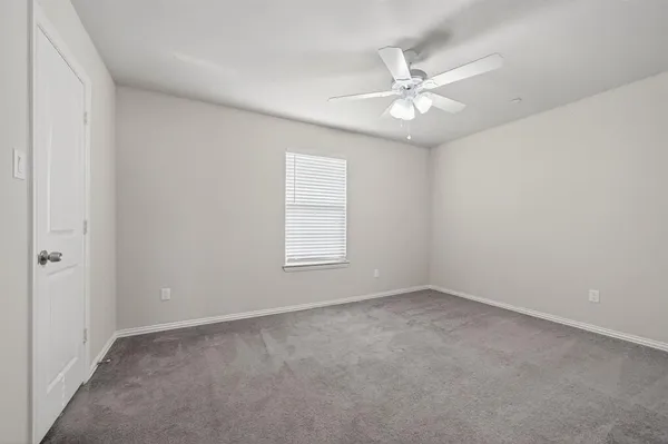 an empty room with a window and a fan
