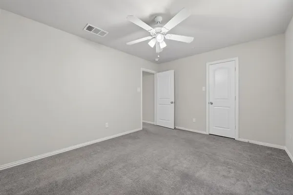an empty room with a chandelier fan and windows